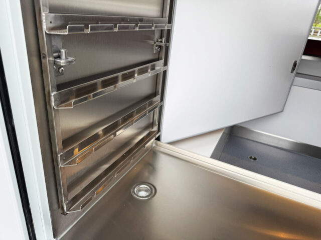Kühlschrank in einem Hähnchengrillmobil mit Edelstahlverkleidung und herausnehmbaren Spießauflagen